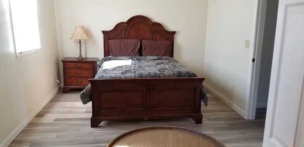 a bed sitting in a bedroom next to a window with wooden floor
