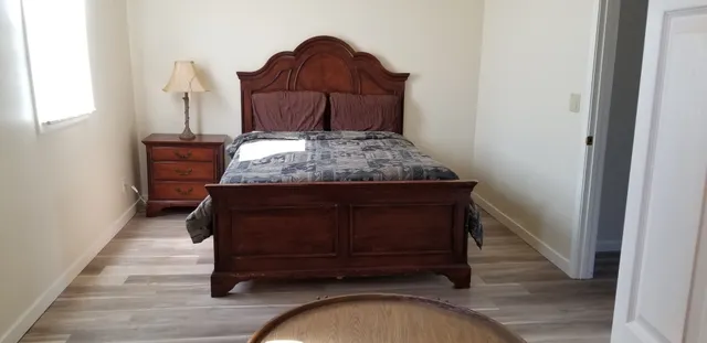 a bed sitting in a bedroom next to a window with wooden floor