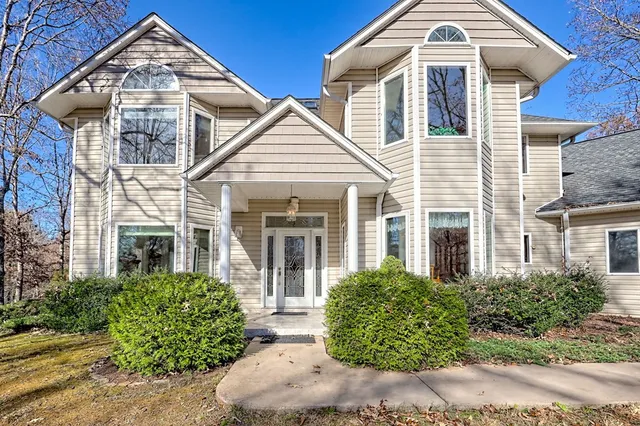 a kitchen with stainless steel appliances kitchen island granite countertop a refrigerator a stove a dining table and chairs with wooden floor