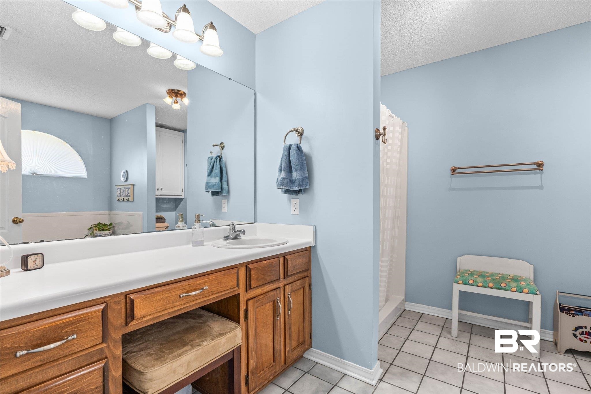 25825 Austin Road Daphne, AL 36526 - Photo 12 of 30 Bathroom featuring vanity, a stall shower, light tile patterned flooring, and a textured ceiling