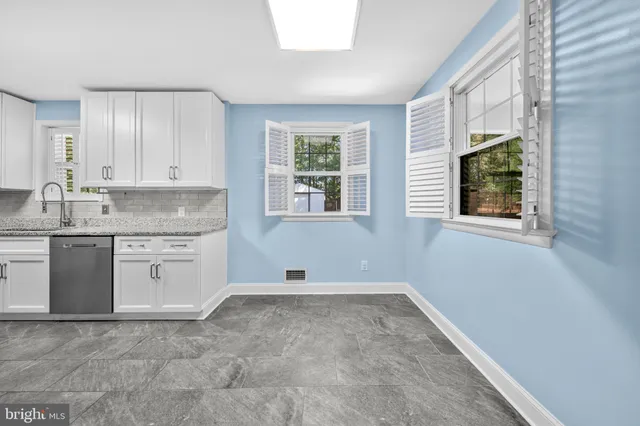 a kitchen with granite countertop white cabinets a stove a sink and a large window