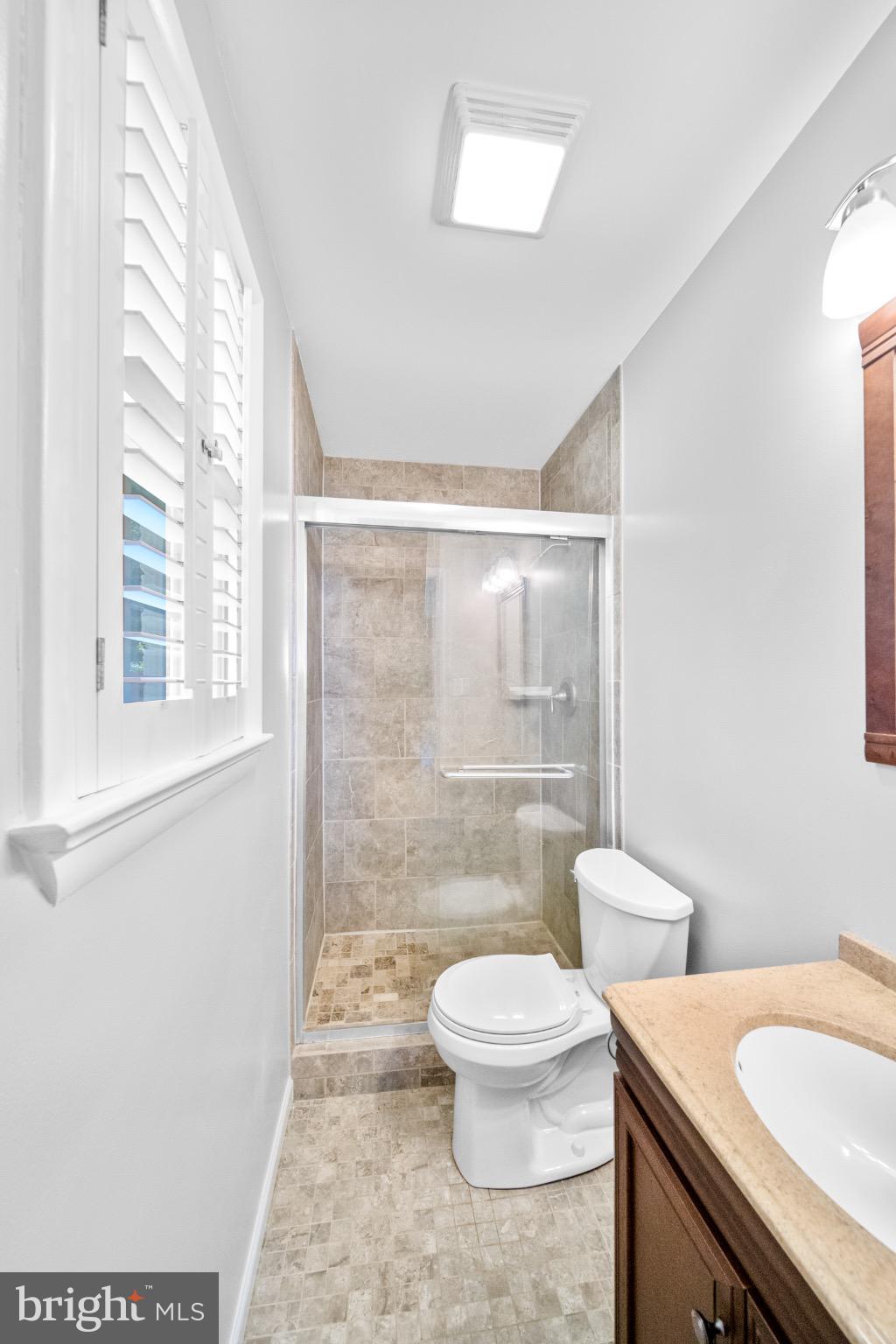 16508 Rolling Tree Road Accokeek, MD 20607 - Photo 24 of 62 a bathroom with a granite countertop sink a toilet a mirror and a shower