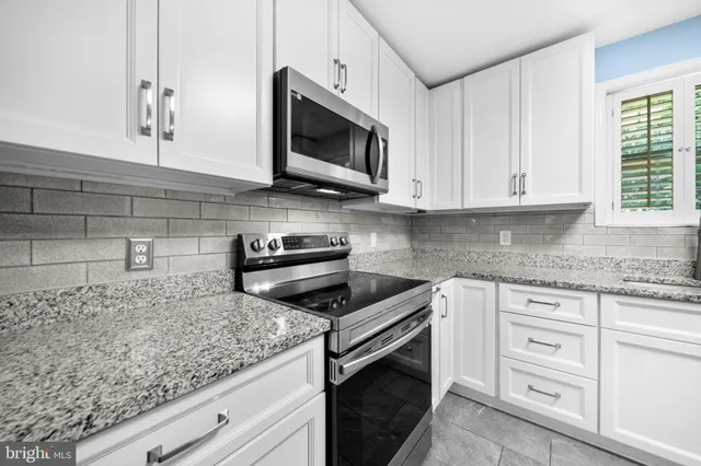 a kitchen with stainless steel appliances granite countertop a refrigerator a sink a stove and oven