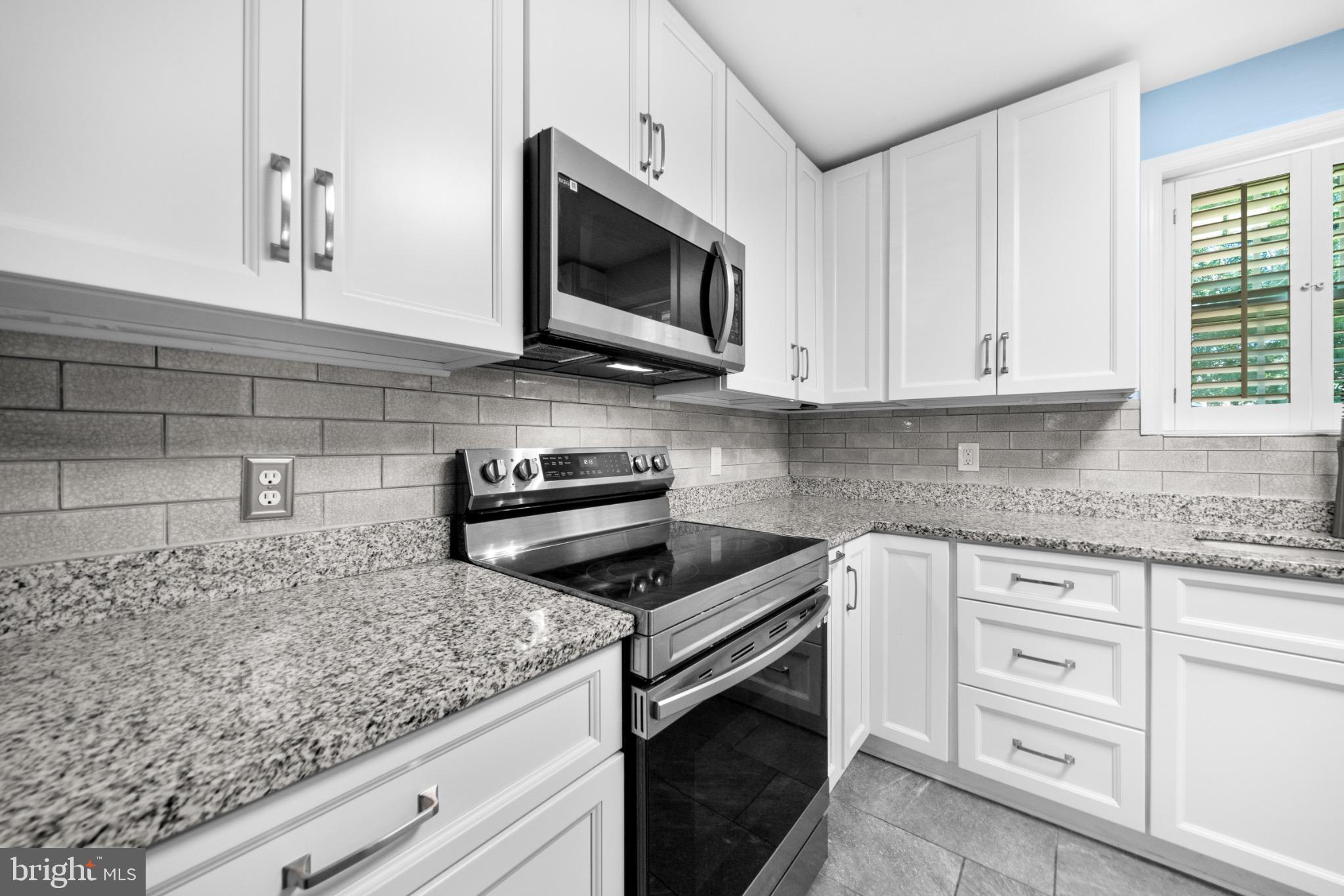 16508 Rolling Tree Road Accokeek, MD 20607 - Photo 5 of 62 a kitchen with granite countertop white cabinets and a stove top oven