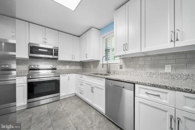 a kitchen with granite countertop a sink and a refrigerator