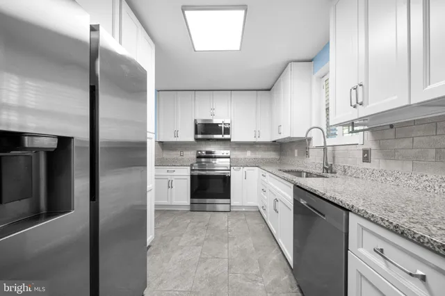 a kitchen with granite countertop white cabinets white appliances and a sink