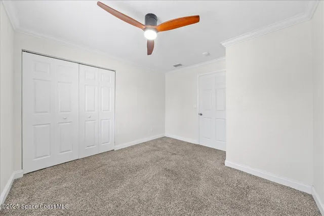 an empty room with a ceiling fan and closet area