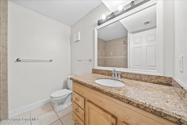 a bathroom with a granite countertop sink a toilet and a shower