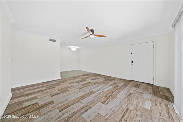 a view of a room with wooden floor and a ceiling fan