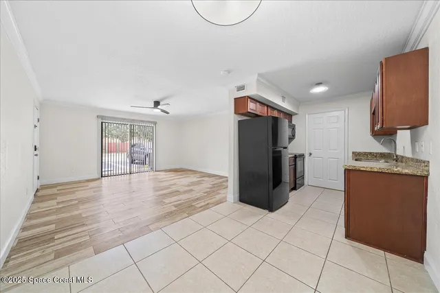 a view of a refrigerator in kitchen and an empty room