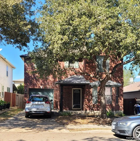 a front view of a house with a large tree