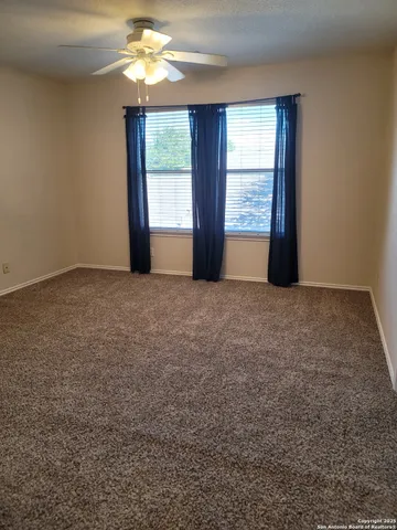 an empty room with windows and chandelier fan