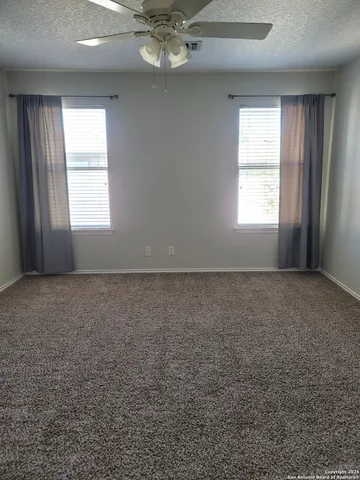 an empty room with a window and ceiling fan