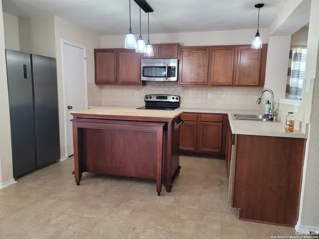 a kitchen with stainless steel appliances granite countertop wooden cabinets a stove top oven a sink and dishwasher
