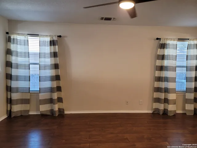 a view of empty room with wooden floor and window