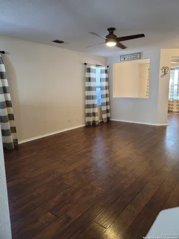 an empty room with wooden floor closet and windows