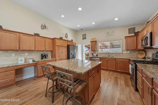 a kitchen with stainless steel appliances granite countertop a sink dishwasher stove and microwave with wooden cabinets