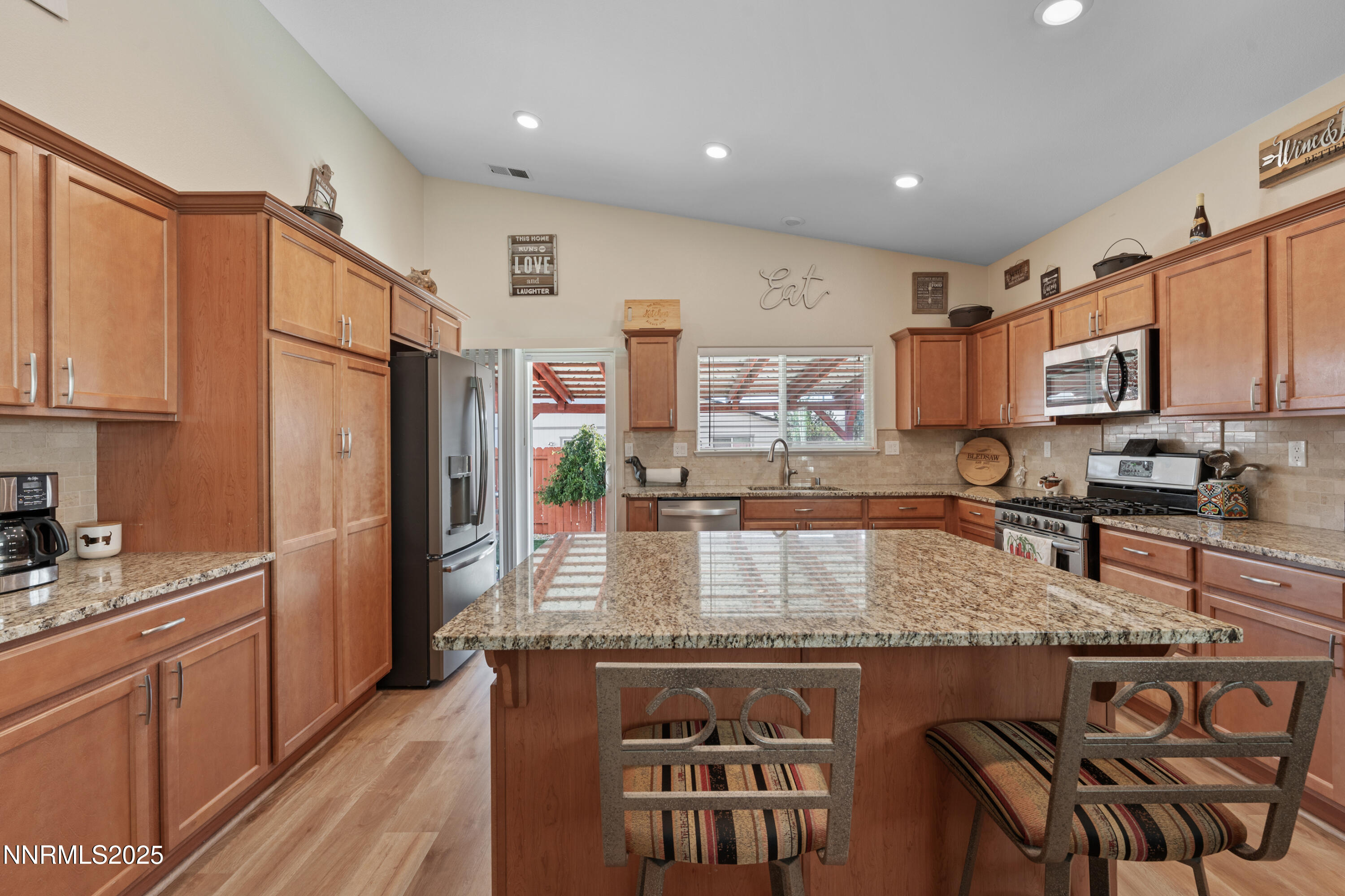 18520 Silverbell Court Reno, NV 89508 - Photo 18 of 60 a kitchen with kitchen island granite countertop a stove top oven a sink dishwasher a dining table and chairs with wooden floor