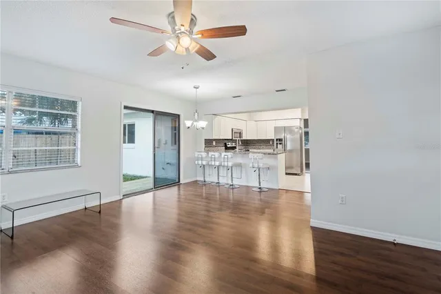a view of an empty room with wooden floor and a ceiling fan