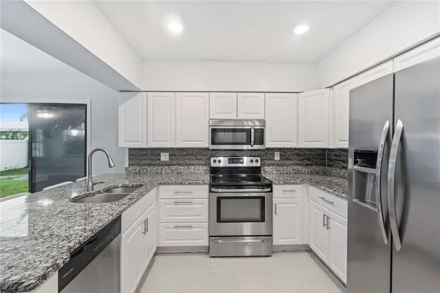 a kitchen with stainless steel appliances granite countertop a stove a sink and a refrigerator