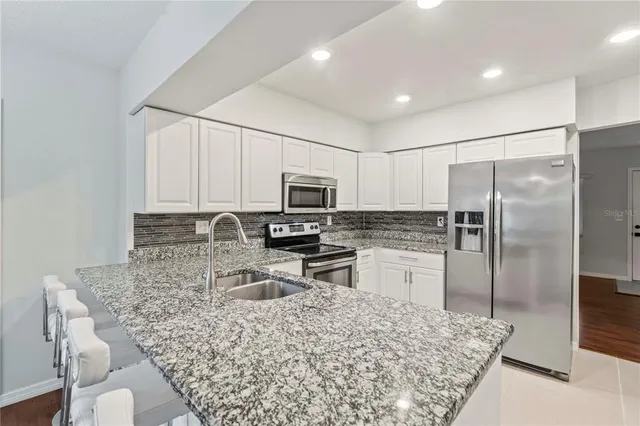 a kitchen with stainless steel appliances granite countertop a sink refrigerator and microwave
