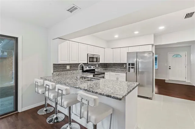 a kitchen with stainless steel appliances granite countertop a kitchen island a stove and a refrigerator