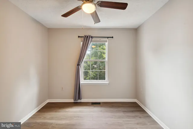 an empty room with windows and fan