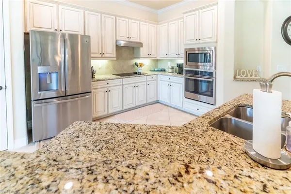 a kitchen with stainless steel appliances kitchen island granite countertop a refrigerator and a sink