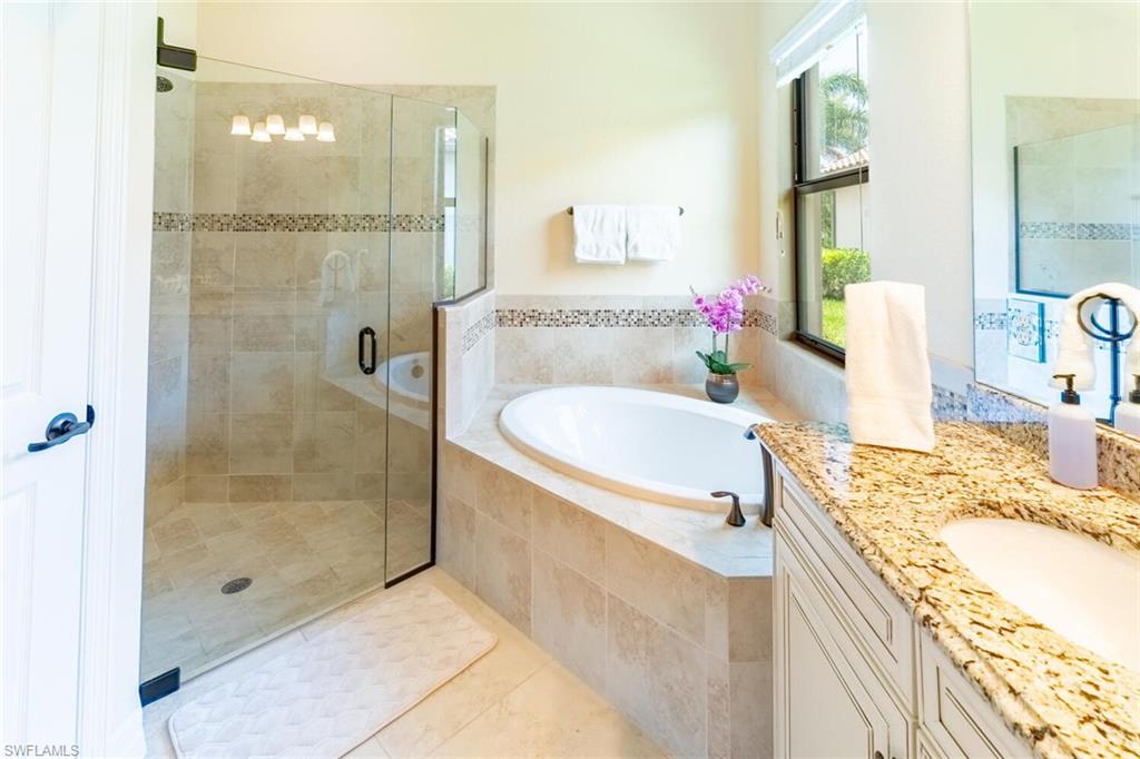 9372 Vercelli Court Naples, FL 34113 - Photo 24 of 50 a bathroom with a granite countertop shower a sink and a mirror