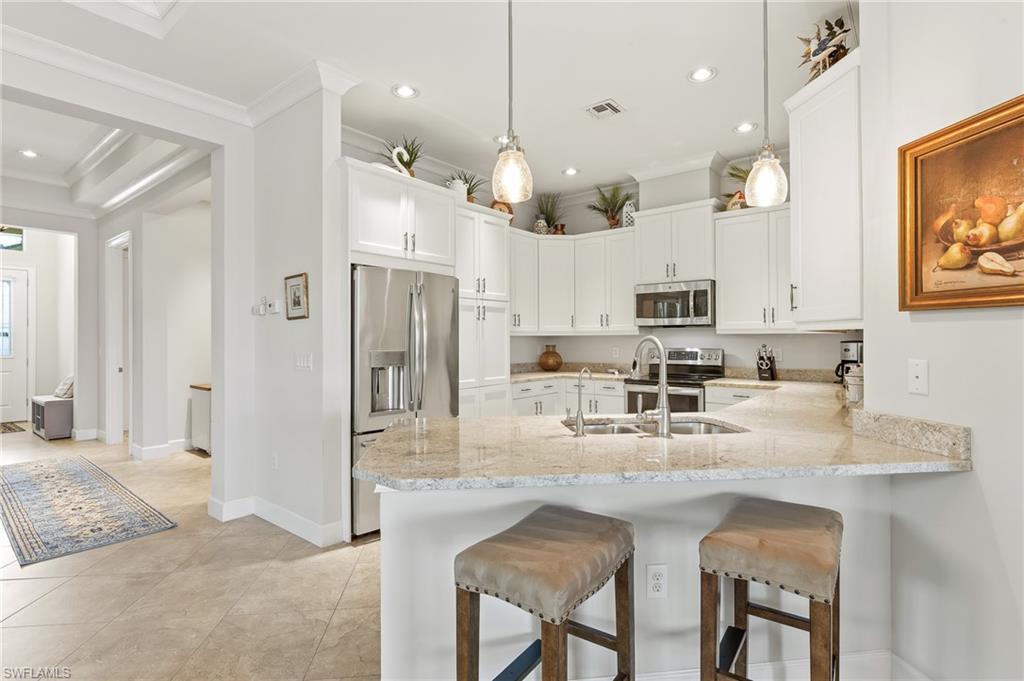 6939 Cay Court Naples, FL 34113 - Photo 5 of 30 a kitchen with stainless steel appliances granite countertop a sink refrigerator and cabinets