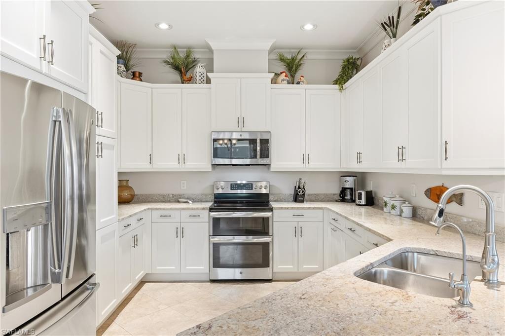6939 Cay Court Naples, FL 34113 - Photo 6 of 30 a kitchen with granite countertop a sink stainless steel appliances and cabinets