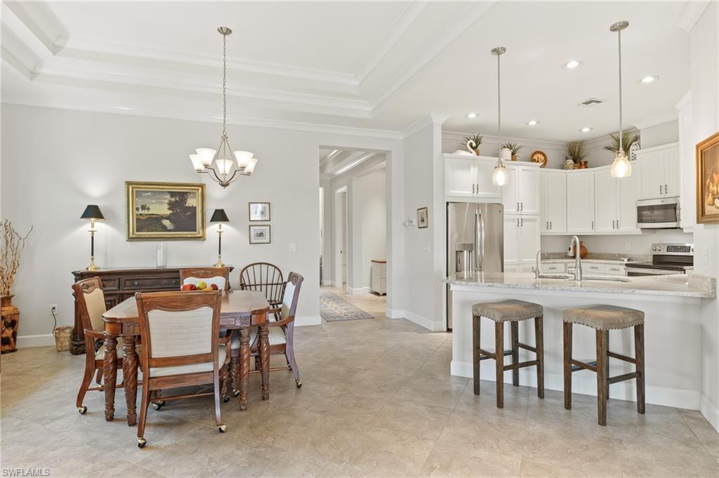 6939 Cay Court Naples, FL 34113 - Photo 7 of 30 a dining room with furniture a chandelier and kitchen view