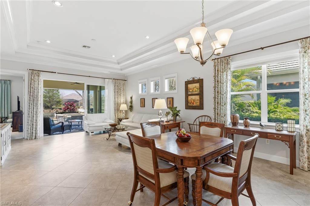 6939 Cay Court Naples, FL 34113 - Photo 8 of 30 a dining room with wooden floor a chandelier a wooden table and chairs