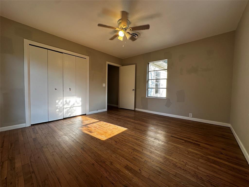 400 East Liberty Street Pilot Point, TX 76258 - Photo 9 of 16 Unfurnished bedroom with dark wood-style floors, a closet, and a ceiling fan