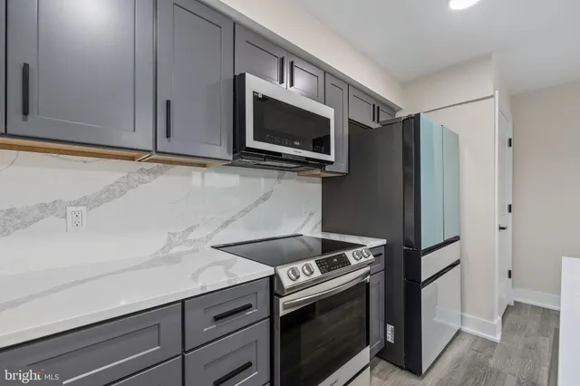 a large kitchen with sink a refrigerator and a wooden floor