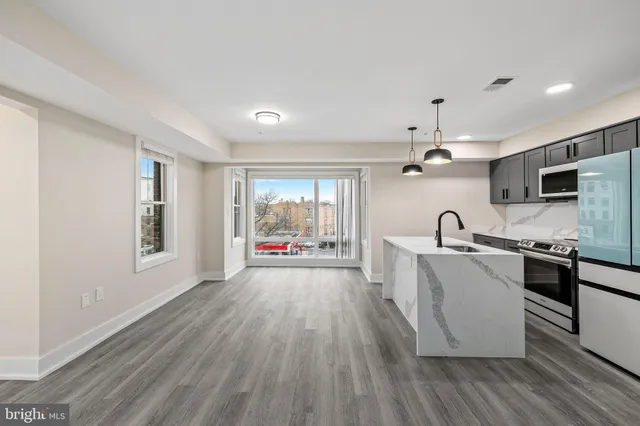 a kitchen with kitchen island a stove a sink a center island with wooden floor and cabinets