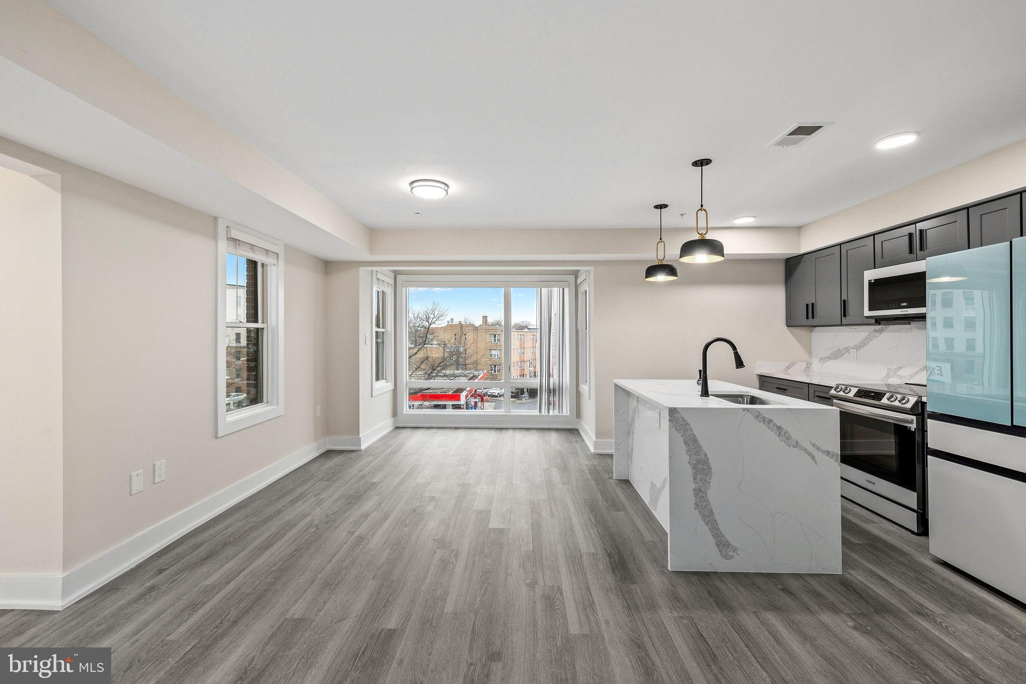 3517 14th Street Northwest, Unit 301 Washington, DC 20010 - Photo 7 of 27 a large kitchen with stainless steel appliances granite countertop a lot of counter space and wooden floor