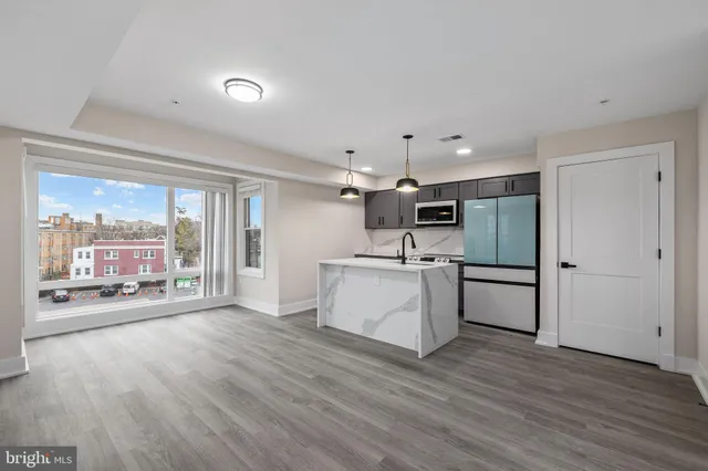 a kitchen with stainless steel appliances a stove top oven a sink dishwasher and a refrigerator with wooden floor