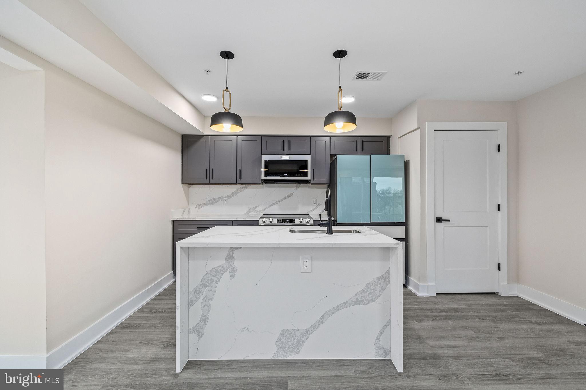 3517 14th Street Northwest, Unit 301 Washington, DC 20010 - Photo 9 of 27 a kitchen with kitchen island a stove a sink a center island with wooden floor and cabinets