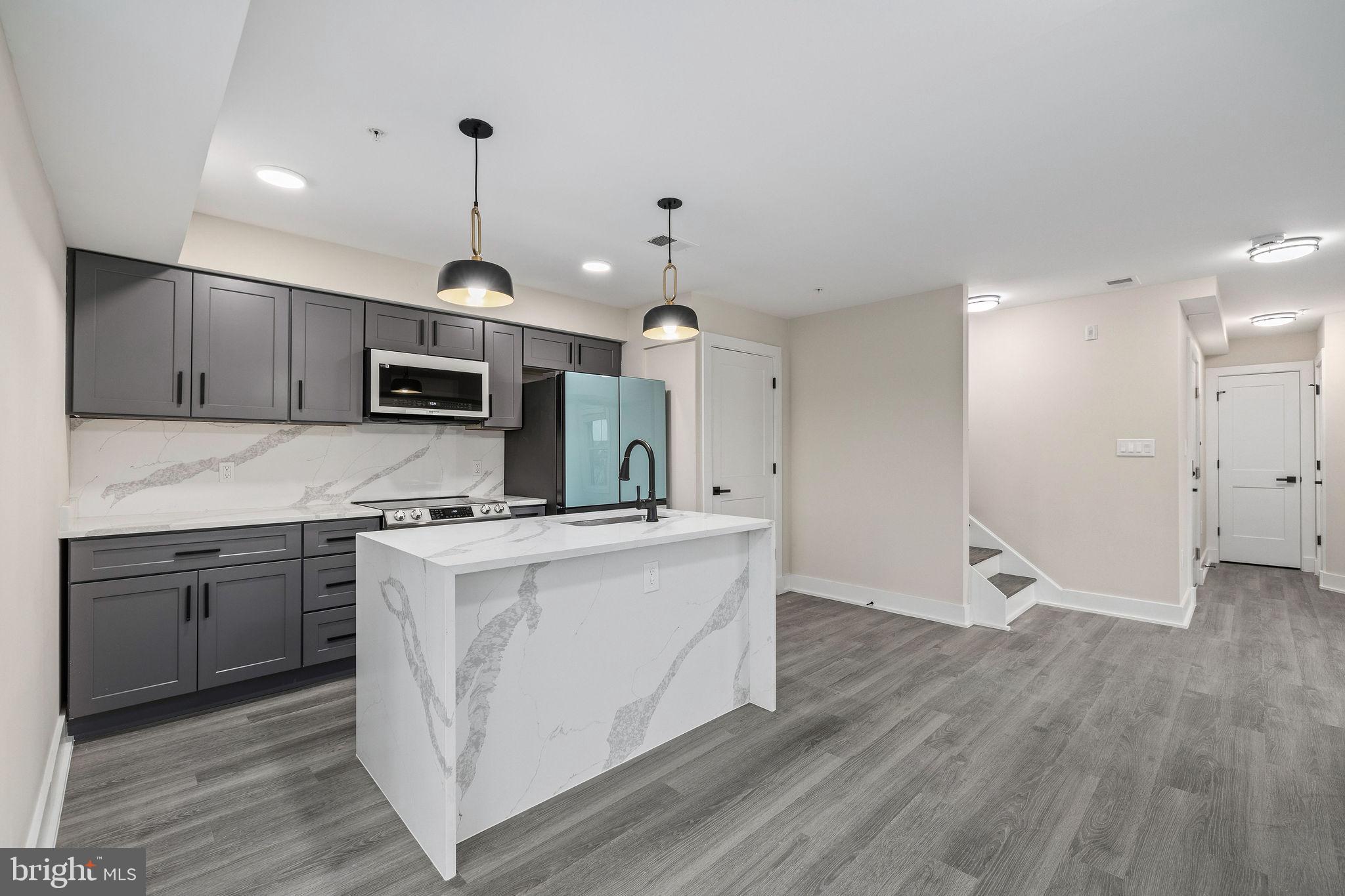3517 14th Street Northwest, Unit 301 Washington, DC 20010 - Photo 10 of 27 a kitchen with stainless steel appliances a stove top oven a sink dishwasher and a refrigerator with wooden floor