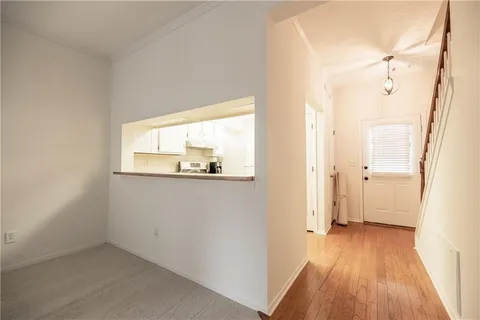 a view of a hallway with wooden floor and a bathroom