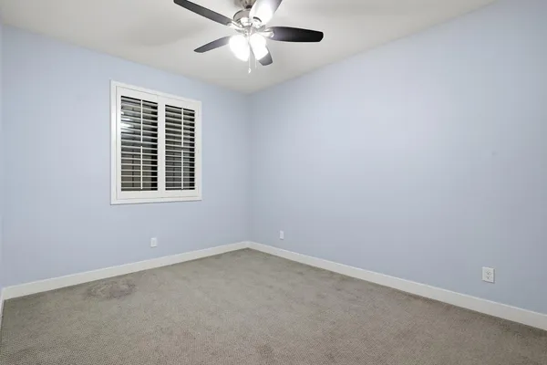 an empty room with a window and a fan