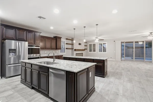 a large kitchen with stainless steel appliances kitchen island granite countertop a stove a sink dishwasher a refrigerator and wooden cabinets with wooden floor