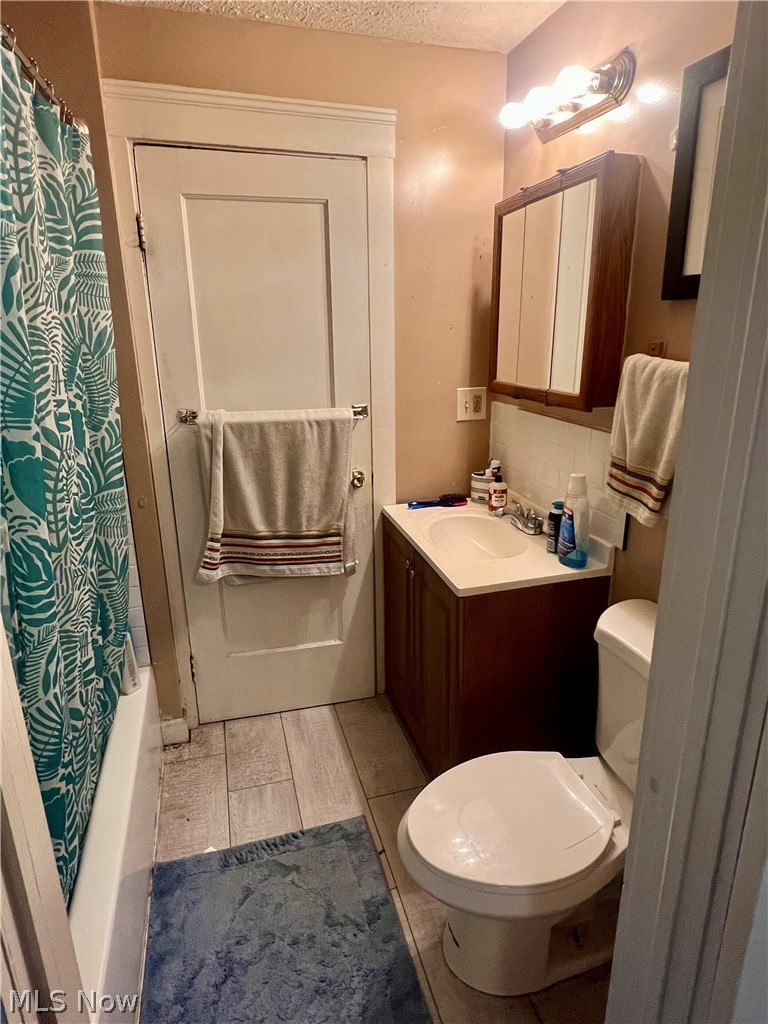 1714 Hillview Road Cleveland, OH 44112 - Photo 10 of 17 Full bathroom with vanity, decorative backsplash, shower / bath combination with curtain, toilet, and tile patterned flooring