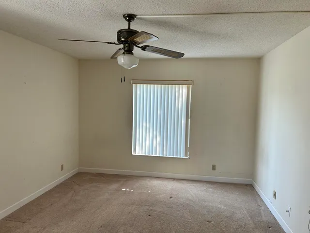 an empty room with a window and a fan