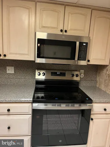 a kitchen with granite countertop white cabinets and stainless steel appliances
