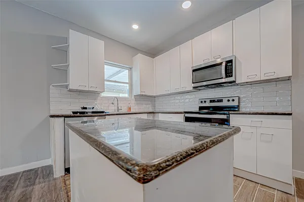 a kitchen with stainless steel appliances granite countertop a sink a stove and microwave