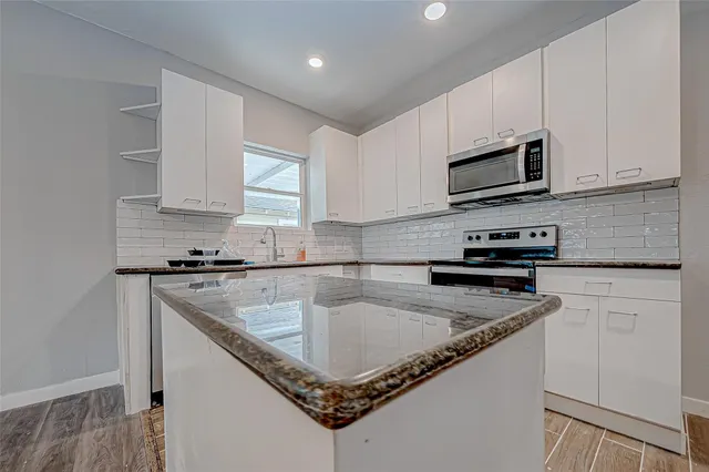 a kitchen with stainless steel appliances granite countertop a sink a stove and microwave