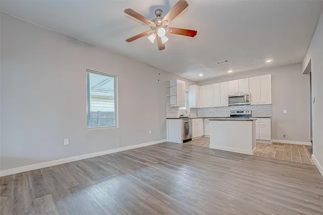 a view of kitchen with granite countertop window and white cabinets