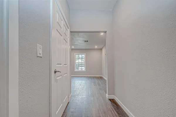 a view of a hallway with wooden floor and a window